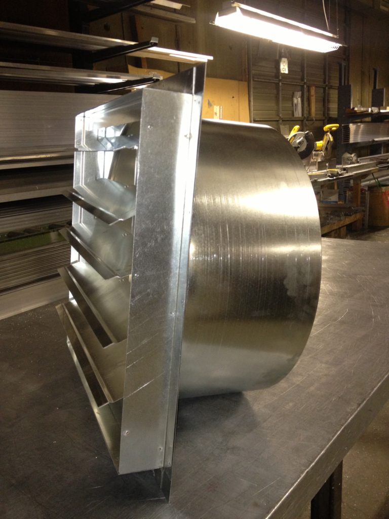 Industrial metal ventilation duct with louvers in a workshop.