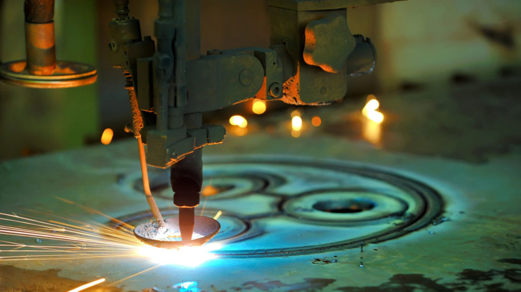 Close-up of a plasma cutter slicing through metal with bright sparks.