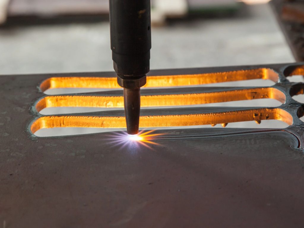 Close-up of a plasma cutter welding metal with sparks flying.