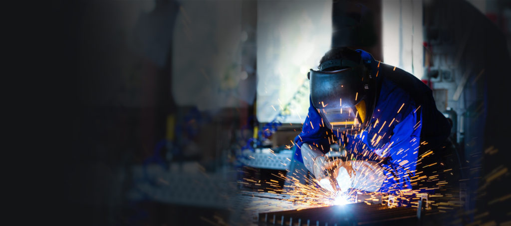 Welder in protective gear sparks bright during metalwork.
